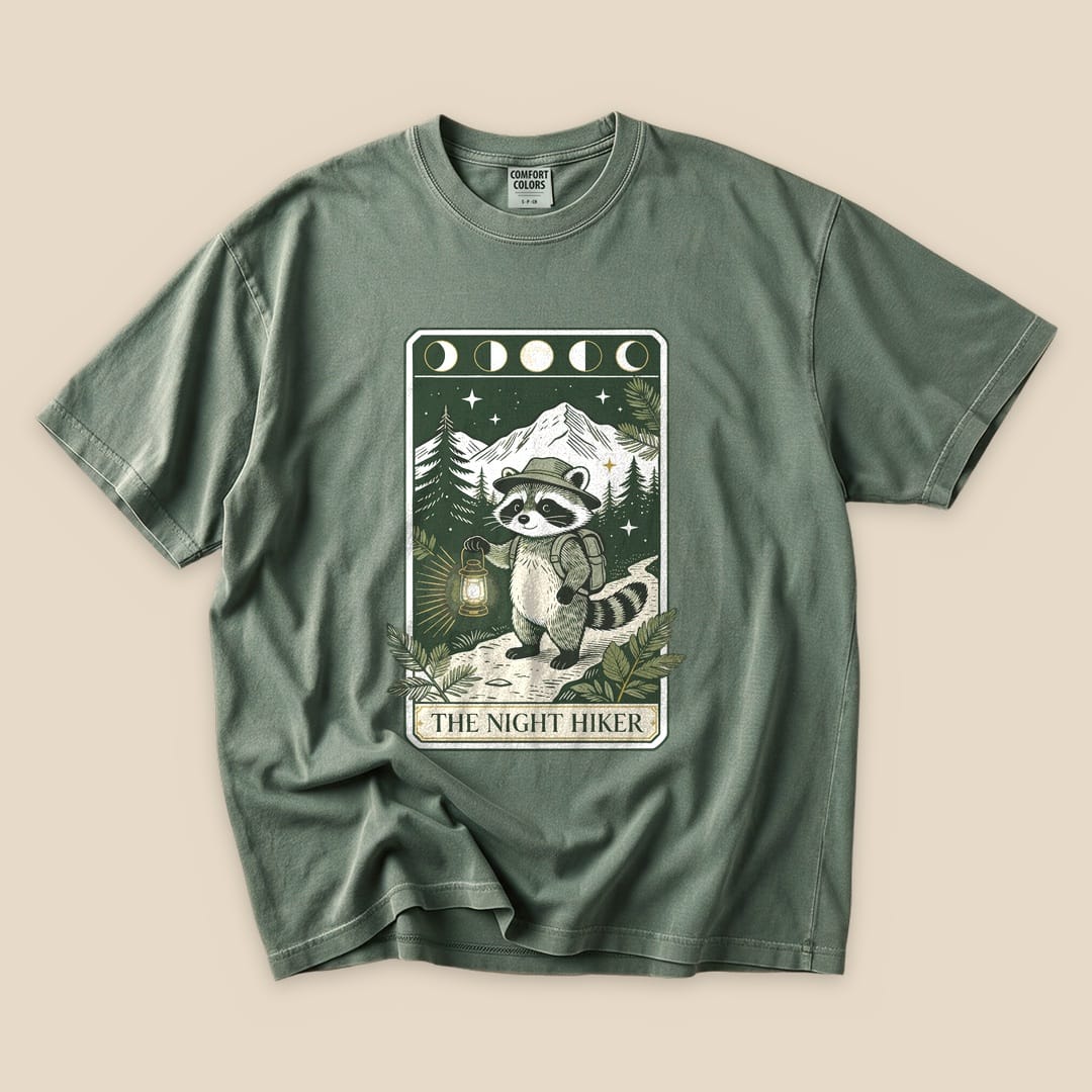 Moss The Night Hiker T-Shirt with a raccoon hiker with a lantern on a moonlit tarot card graphic