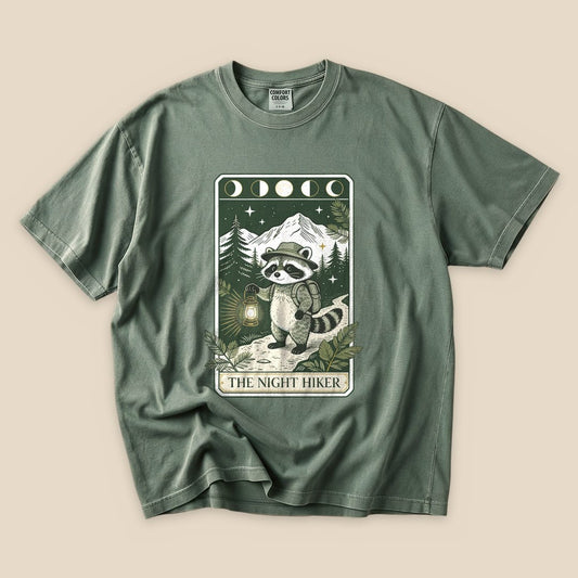 Moss The Night Hiker T-Shirt with a raccoon hiker with a lantern on a moonlit tarot card graphic