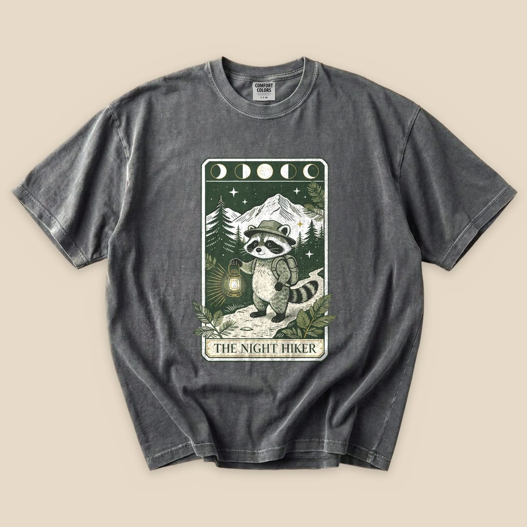 Pepper The Night Hiker T-Shirt with a raccoon hiker with a lantern on a moonlit tarot card graphic