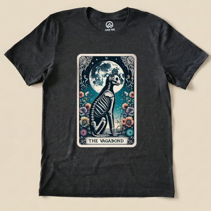 A graphic t-shirt featuring "The Vagabond Tarot Card Cat Shirt" design, showcasing a skeleton cat sitting by a full moon and flowers.