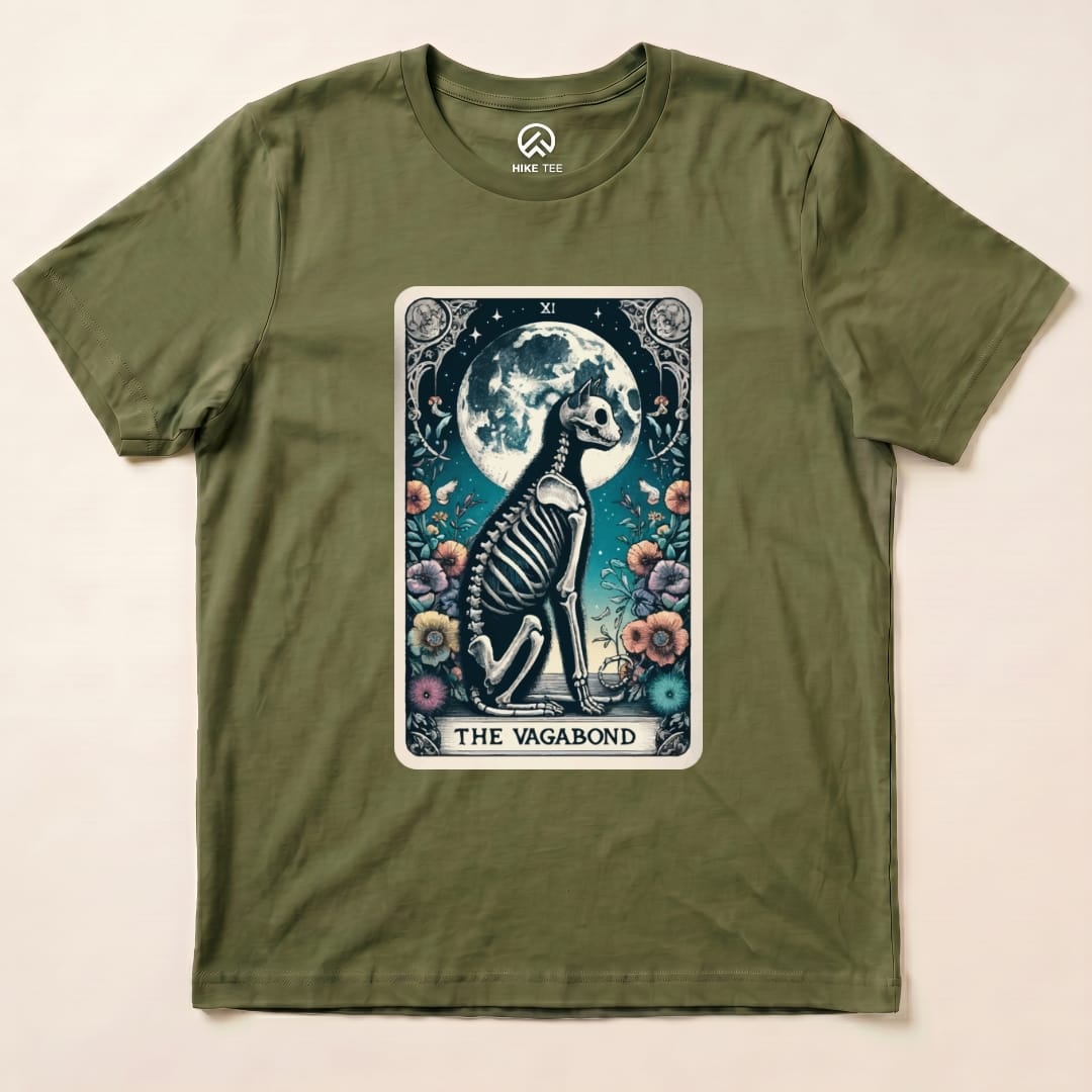 A graphic t-shirt featuring "The Vagabond Tarot Card Cat Shirt" design with a skeleton cat sitting in front of a full moon and flowers.