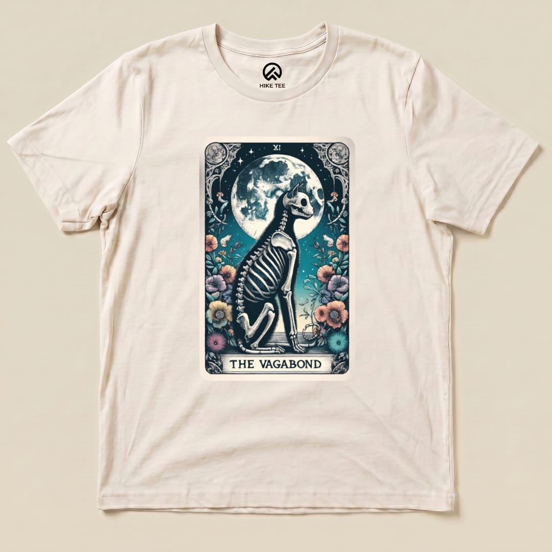 The Vagabond Tarot Card Cat Shirt features an illustrated skeleton cat sitting among colorful flowers and a full moon backdrop.