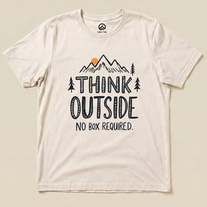 A cream graphic t-shirt featuring the slogan "THINK OUTSIDE" above an illustration of mountains and trees, with "NO BOX REQUIRED.