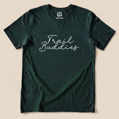 Graphic t-shirt featuring the words "Trail Buddies" printed in a playful, cursive font on a dark green background.
