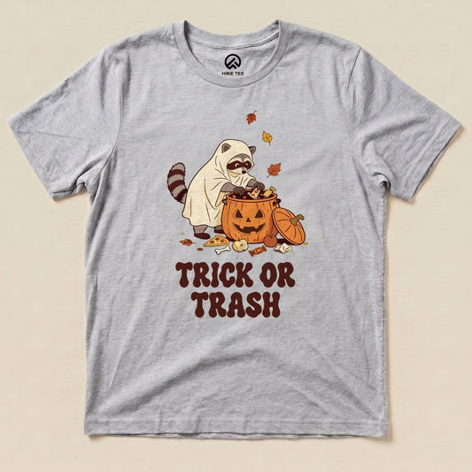 Athletic Heather Trick or Trash Shirt with a raccoon in a ghost costume raiding a pumpkin candy bucket graphic