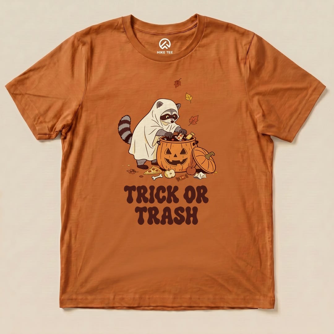 Autumn Trick or Trash Shirt with a raccoon in a ghost costume raiding a pumpkin candy bucket graphic