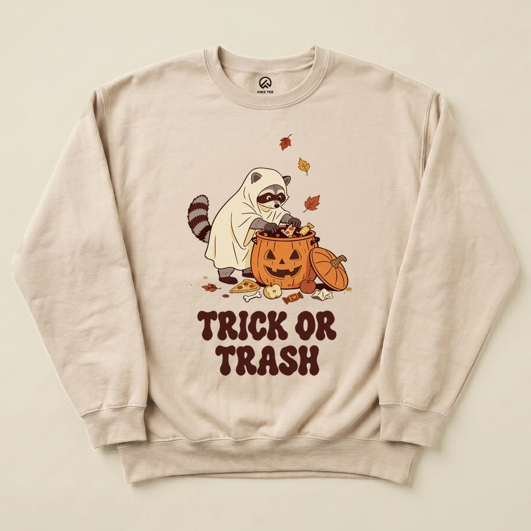 Sand Trick or Trash Sweatshirt with a raccoon in a ghost costume raiding a pumpkin candy bucket graphic