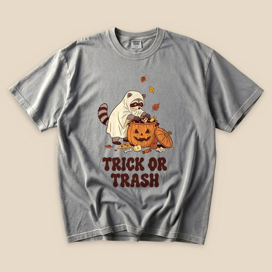 Grey Trick or Trash T-Shirt with a raccoon in a ghost costume raiding a pumpkin candy bucket graphic