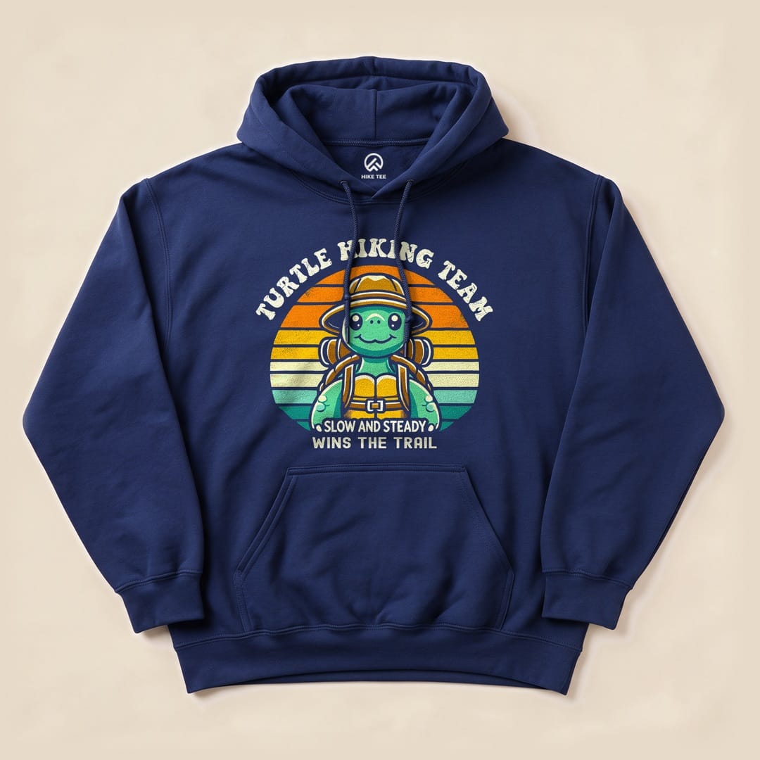 A navy hoodie featuring a graphic of a turtle wearing a hiking backpack, with the text "Turtle Hiking Team" and "Slow and Steady Wins the Trail.