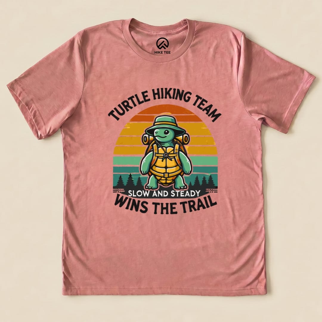 A graphic t-shirt featuring a turtle in hiking gear with the slogan "Turtle Hiking Team Slow and Steady Wins the Trail Shirt.