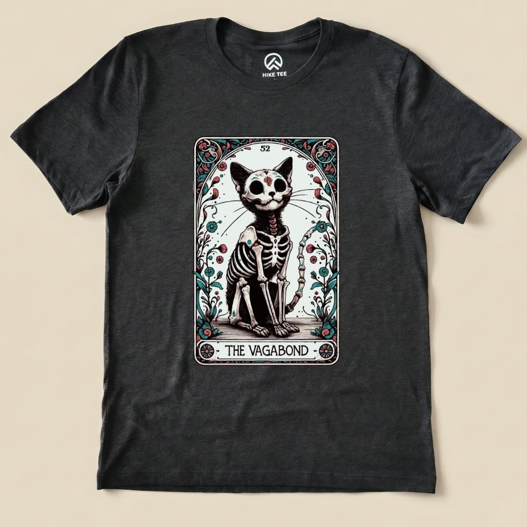 The graphic t-shirt features a whimsical illustration of a skeletal cat in a tarot card design, labeled "The Vagabond.