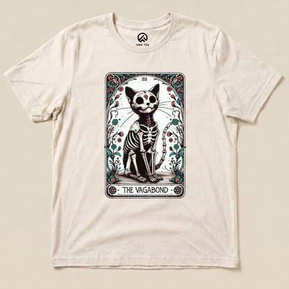 A graphic t-shirt featuring a cartoonish skeleton cat design inside a tarot card frame, labeled "THE VAGABOND.