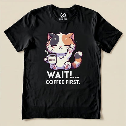 A graphic t-shirt featuring a cute cat holding a coffee mug with the text "WAIT!... COFFEE FIRST." on a black background.