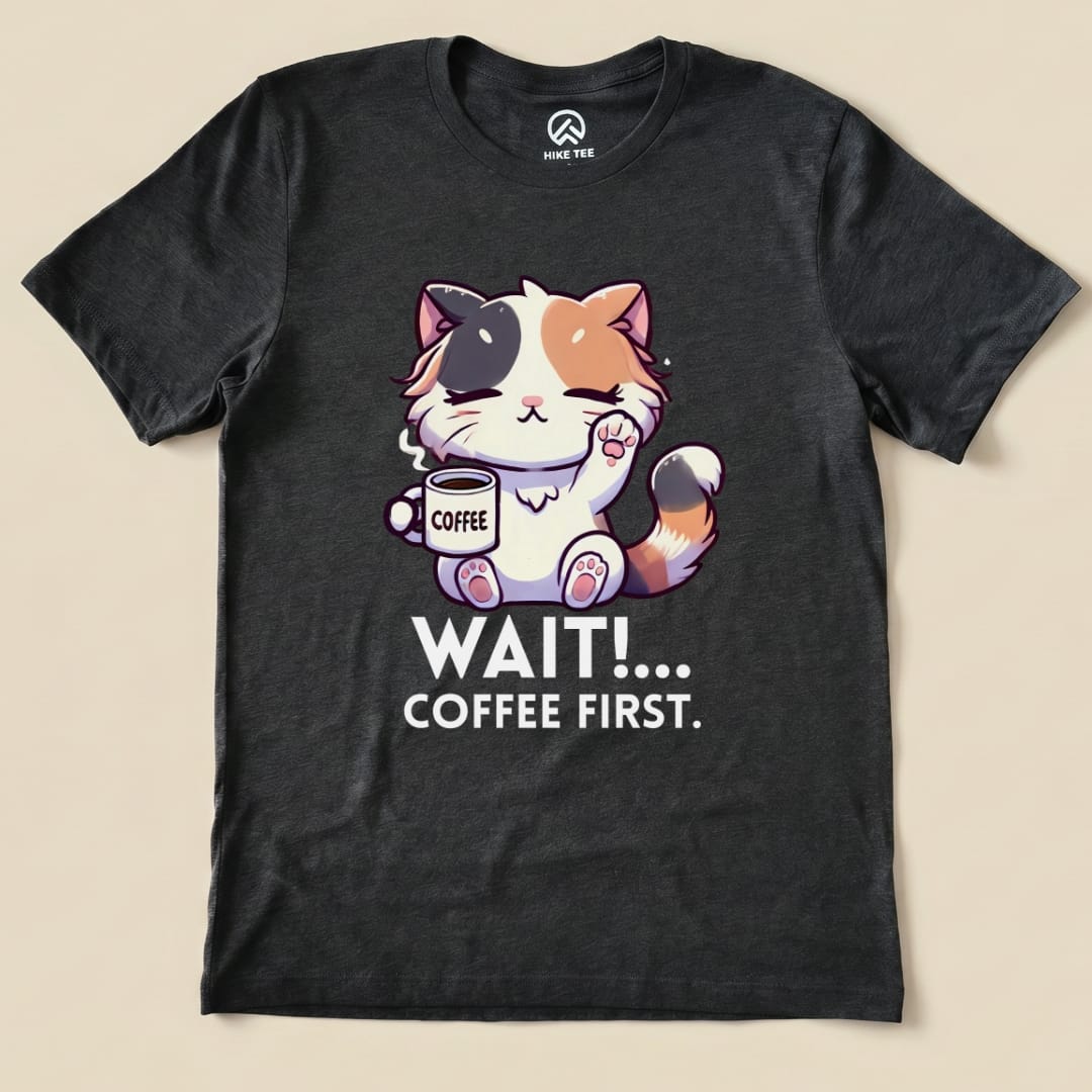 A black graphic t-shirt features a cute cartoon cat holding a coffee cup with the text "WAIT!... COFFEE FIRST.