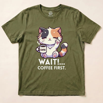 Graphic t-shirt featuring a cute cat holding a coffee cup with the text "WAIT!... COFFEE FIRST" on an olive green background.