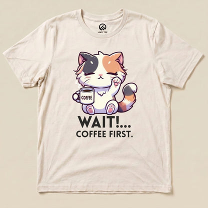 A graphic t-shirt featuring an adorable cat holding a coffee cup and the phrase "WAIT!... COFFEE FIRST.