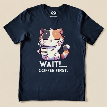 A navy graphic t-shirt featuring a cute cat holding a coffee cup with the text "WAIT!... COFFEE FIRST." printed below.