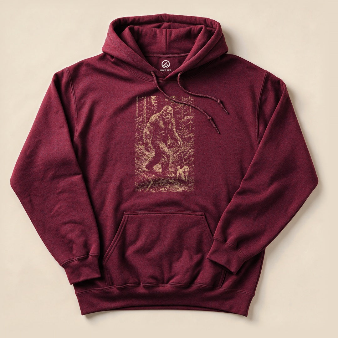 A maroon "Walking the Dog Hoodie" features a graphic of a Bigfoot walking alongside a small dog in a forest setting.