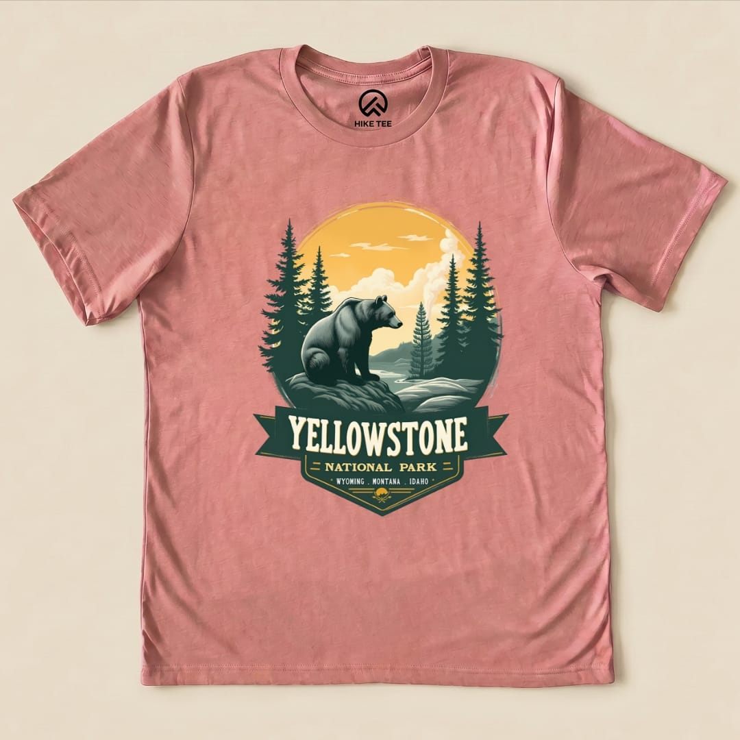 A pink graphic t-shirt features a Yellowstone Grizzly Bear Shirt design with a bear, forest, and sunset in a national park theme.