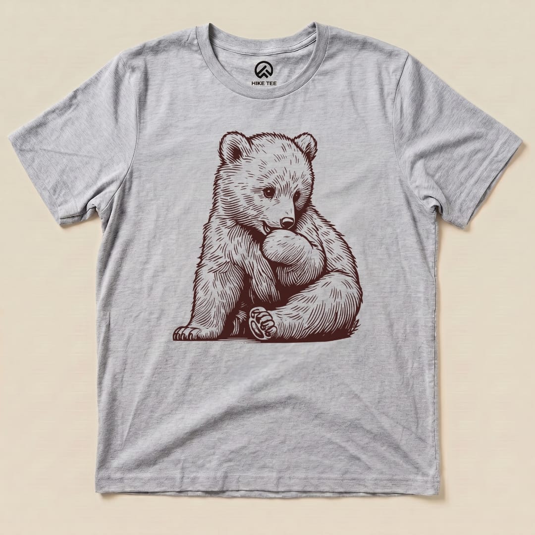A graphic t-shirt featuring a cute bear illustration, labeled as the "Youth Bear Shirt," set against a light background.