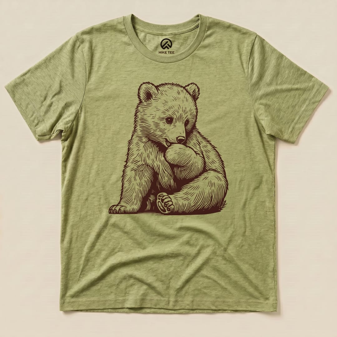 A graphic t-shirt depicting a cute bear cub hugging a rock is the design featured on the Youth Bear Shirt.
