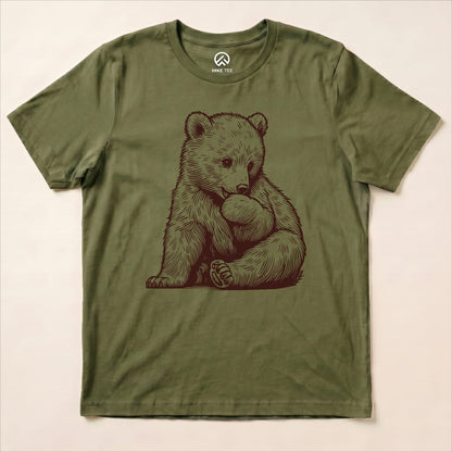 A graphic t-shirt featuring an adorable illustration of a bear cuddling a ball, in a muted olive green color, labeled as "Youth Bear Shirt.