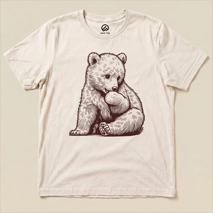 Graphic t-shirt featuring an adorable bear cub sitting and holding its paw on a light background, labeled as "Youth Bear Shirt.