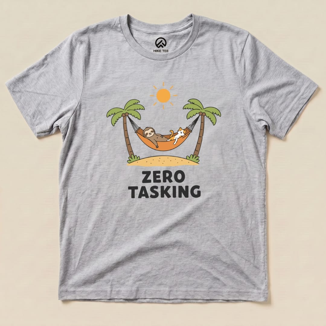 A graphic t-shirt featuring a sloth and cat lounging in a hammock under palm trees with the text "ZERO TASKING" below.