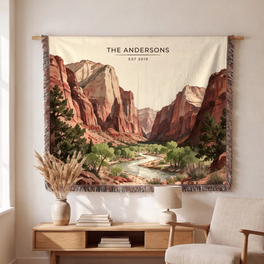 A beautifully designed Zion Canyon River Woven Blanket hangs on a wall, showcasing a vibrant canyon landscape with greenery.